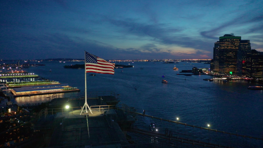 closer sunset flying left view of American flag atop Brooklyn Bridge