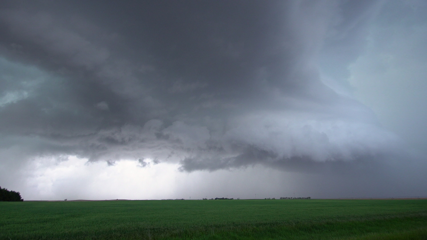 View of severe storm rolling over farm fields in Nebraska as lightning flashes in the sky as clouds spin.