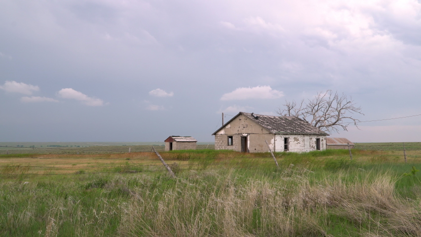 Old house on the prairie in Colorado as grass blows in the wind as storm moves in from behind.