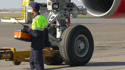 aircraft maintenance. Airport airplane mechanic, worker technical staff towing tow tractor tug pushing airbus. Vehicle car towing aircraft to runway of Airport, Airliner being Pulled Towards Terminal