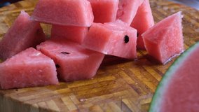 Bite size watermelon on wooden table. Selective focus. Panning to the right.
