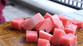 Bite size watermelon on wooden table. Selective focus. Panning to the right.
