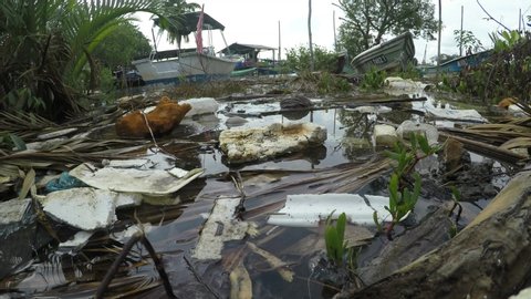 MERSING, MALAYSIA - 6 JUNE 2019: Water pollution. Plastic and styrofoam bottles, bags and food containers dumped in river and flow into sea	