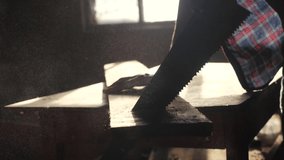 carpenter handmade and craft concept slow motion video. carpenter sawing a tree in a workshop sawing sunlight from lifestyle a window silhouette. woodworker engaged handmade in processing wood at the