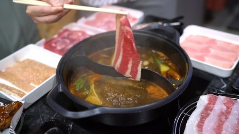 
Holding sliced beef (wagyu) using chopsticks on hot pot with smoke for Japanese hot pot also known as Shabu Shabu or Sukiyaki is Japanese style. 