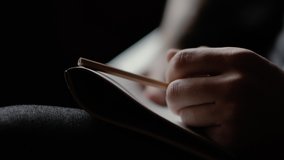 Close-up man's hand knocks nervously on the notebook with pencil and starts writing on dark background. Person thinks at the cafe. Guy is considering a solution to the problem - Powered by Shutterstock - Get 15% off with code: PIKWIZARD15