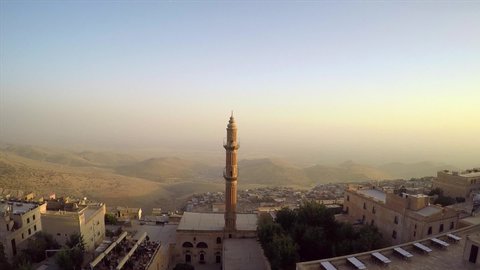 Drone flying over historic Mardin city in Turkey southeast passing the stone minaret in the middle mosque in summer