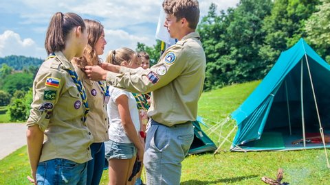 DOMZALE, SLOVENIA - 10. JULY 2018 A leader of this scouts team is making sure that neckerchiefs around their necks stand okay.