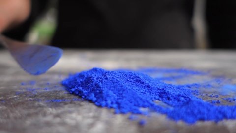 Artist prepering blue powder pigment on table in workshop, closeup