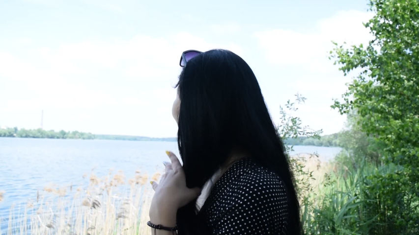 View of the brunette girl over the lake. Summer landscape