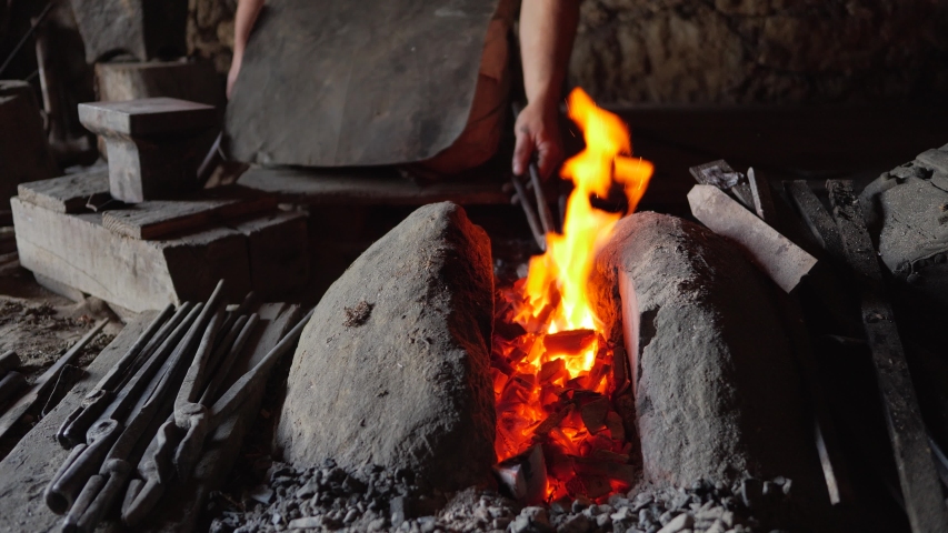blacksmith working metal with hammer on the anvil in the forge