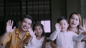 Happy family with kids waving hand while making video call at home