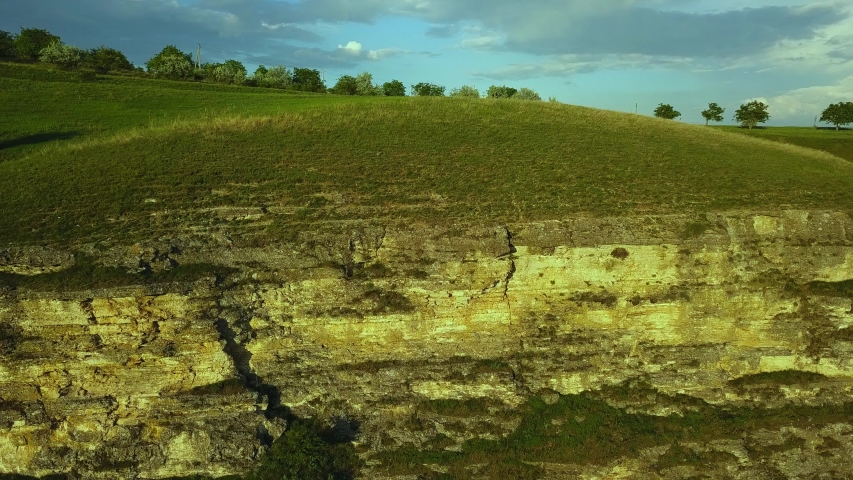 Aerial view. The camera flies over a beautiful deep canyon with rocky cliffs and snowy peaks in the background. Amazing mountain landscape.