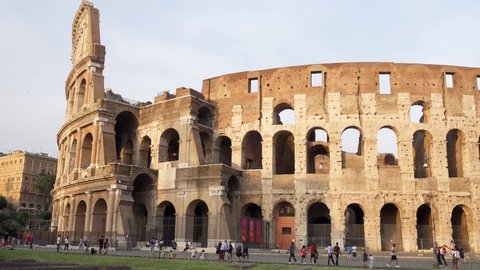 Famous Italian attraction Colosseum in Rome. Veiw on ancient Flavius amphitheater Coliseum in capital of Italy. Unrecognizable people walking in front of attraction. Camera moving from left to right