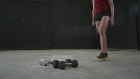 Fit sportswoman entering room, taking two dumbbells from floor and starting weightlifting workout, man talking to camera and recording sports video blog