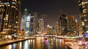Stunning time-lapse video of boats sailing on the artificial canal in Dubai Marina. Illuminated skyscrapers surround a beautiful promenade. Dubai, United Arab Emirates.