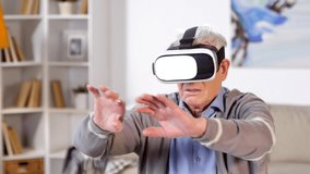 Medium shot of aged Caucasian man sitting with virtual reality headset, watching videos and moving his hands - Powered by Shutterstock - Get 15% off with code: PIKWIZARD15