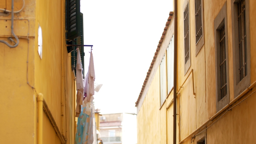 A view of a roofs on the alley on the left a balcony with laundry