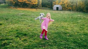 A child model smiling and playing with her toy Bunny and a large green field with beautiful autumn leaves on the trees behind her.