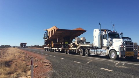 ALICE SPRINGS,NT-MAY 15 2019:Oversize vehicle convoy on Stuart highway in the red center of Australia outback.Load shifting in the responsibility of the shipper, motor carrier, driver and the receiver