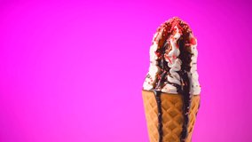 Ice cream cone melting time lapse. Close-up of Ice cream with Colorful sprinkles and chocolate syrup topping. Icecream in waffle cone, on pink background. White Sweet dessert 4K UHD