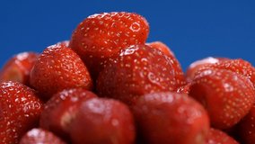 Fresh red Strawberries rotate, closeup video. Many juicy ripe berries strawberries on blue background.
