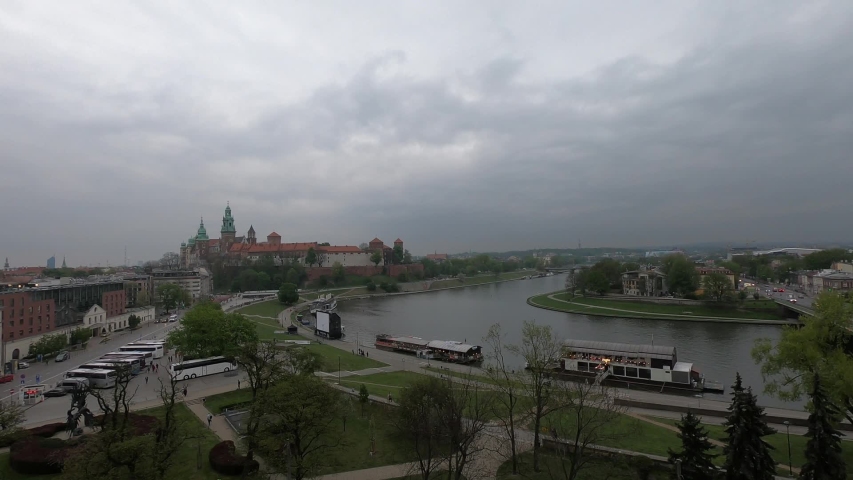 The Wawel Royal Castle and Cathedral Basilica in Krakow, Poland. Tourist boats on Vistula river. Clouds flying over Wawel Royal Castle from across Wistula river on a cloudy day in Spring.