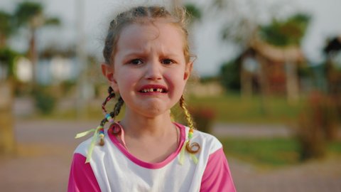 Close up portrait of hardly crying caucasian little girl without tooth. tears streaming down her face.  Real human emotions. Children face wet from tears. 4k