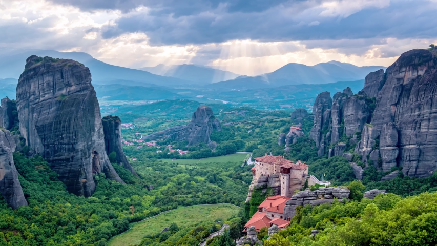 Timelapse of sunset with sun rays over monastery of Rousanou and Monastery of St. Nicholas Anapavsa in famous greek tourist destination Meteora in Greece