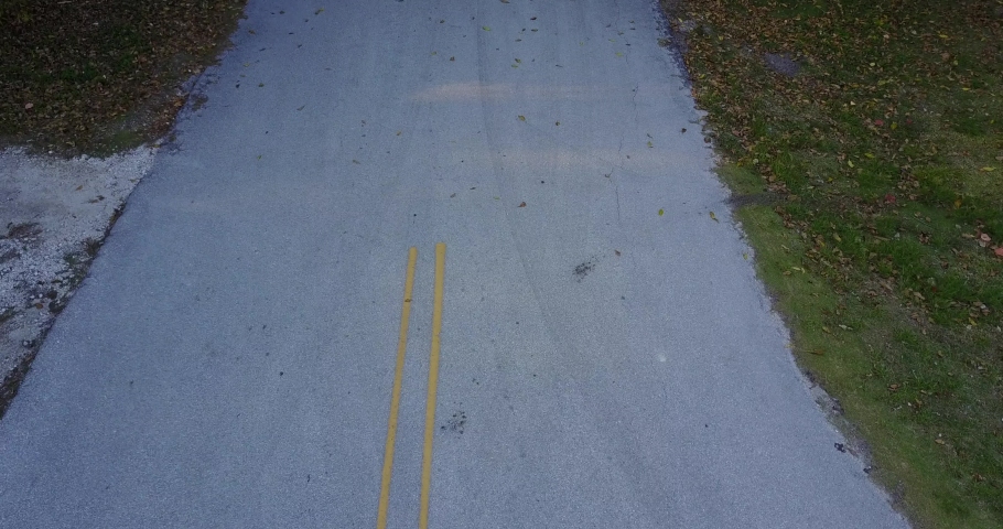 AERIAL: over head shot of a girl skate boarding down a road in Key Largo, Florida on a nice day.