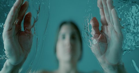 slow motion of a woman washing her face through a glass. detail from the bottom of a woman washing her face