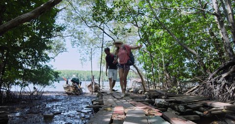 Couple walking on wood pier towards long tail boat transport, on an adventure in Thailand. Shot on red, slow motion.