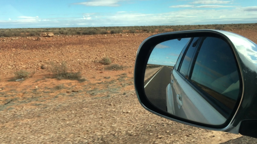 Reflection of Stuart Highway road and central Australia Outback landscape as view from a car wing mirror during a rod trip in the red center of Australia.No people Copy space Royalty-Free Stock Footage #1031410118