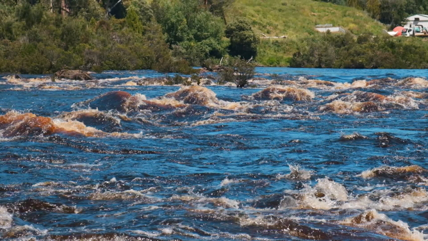 Dirty water flows through the Huon river in Tasmania. Small waves arise. Australia