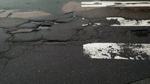 Pothole road cracks problem of Riga city Latvia withing traffic, medium shot