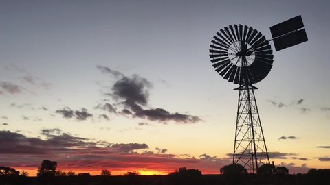 Silhouette of a large windmill in central Australia rotating in slow motion against dramatic Australian outback sunset. No people. Copy space