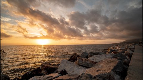Golden wavesing timelapse of sunrise at harbor of Mitilini / Mytilene in Lesvos, Greece with beautiful clouds looking over the aegean sea in the mediterranean, overlooking the Turkish coast,