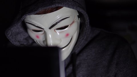 Kinmel Bay, Conwy / Wales - June 3rd 2019 : Masked Anonymous Hacker In Front Of Computer Screen, 4K.