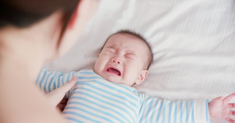 asian baby lying on the bed and crying
