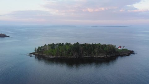 Slide past Curtis Island Lighthouse with pink sunset clouds in the background AERIAL