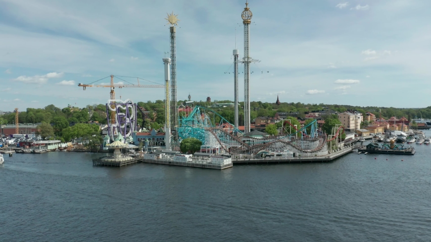 Ascending aerial view over the beautiful located amusement park Grona Lund Tivoli in Stockholm. Full view of the park and waterfront.
