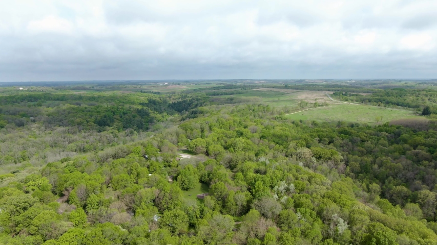 Aerial flight over a campground in Wisconsin, USA. A small building can be seen through the foliage and multiple tents and campers.
