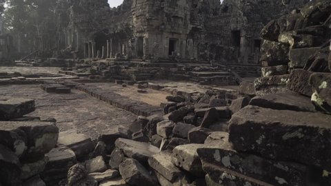 Tilt up to the ancient ruins of Bayon temple glowing in the late afternoon sun; Siem Reap, Cambodia.
