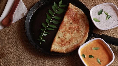 Rotating Masala Dosa / Indian Savory Crepes with potato filling , top down view on wood background