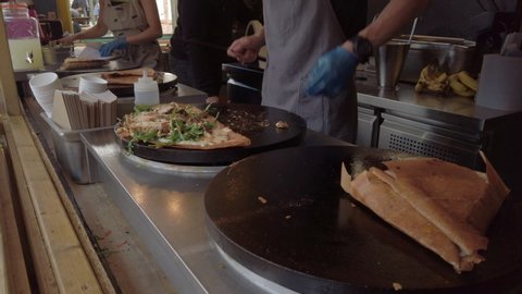 Savoury crepes being cooked on an open-air hotplate at a market stall in York, UK. Slow zoom in.