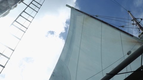 Mainsail billowing in the wind on a sunny clear day, low angle view from the deck.