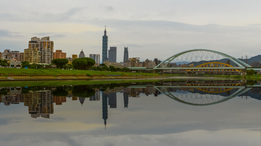 Beautiful Time lapse of Day to Night of Taipei city skyline from afar with Taipei 101 and national landmarks reflection at dusk by Keelung river. 