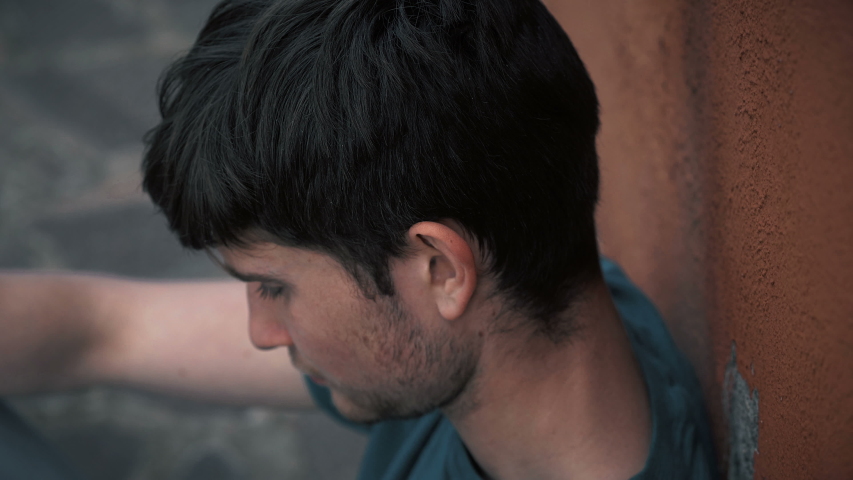 Serious confident young man turning and staring at camera- oudoor