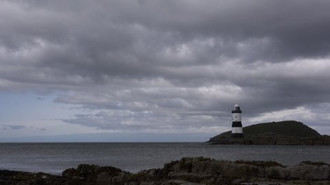 Time lapse of dark clouds moving over a lighthouse in Wales UK 4K