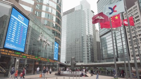 Hong Kong - May 4, 2019: Scenic view of Exchange Square at downtown. The flag of Hong Kong and other flags fluttering over the square. Financial market ticker tape of the Stock Exchange of Hong Kong.